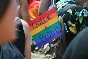 Bendera pelangi dalam protes bertuliskan "queer and proud"
